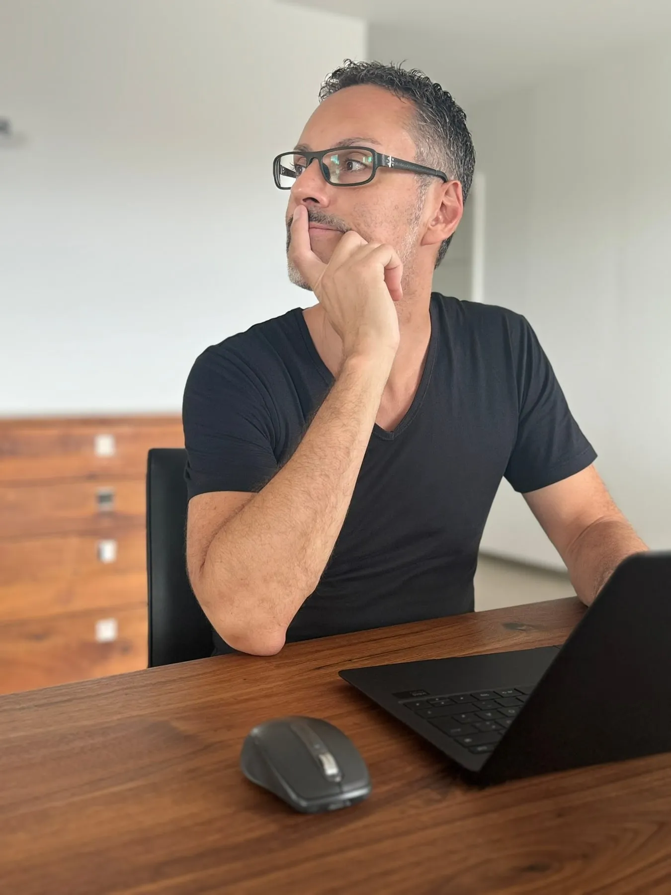 Patrick Schmid am Schreibtisch, zuhörend, die Hand am Kinn
