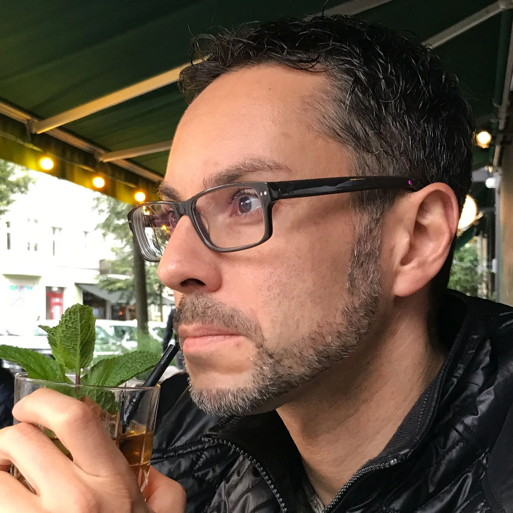 Patrick Schmid mit einem Getränk in einem Straßencafé