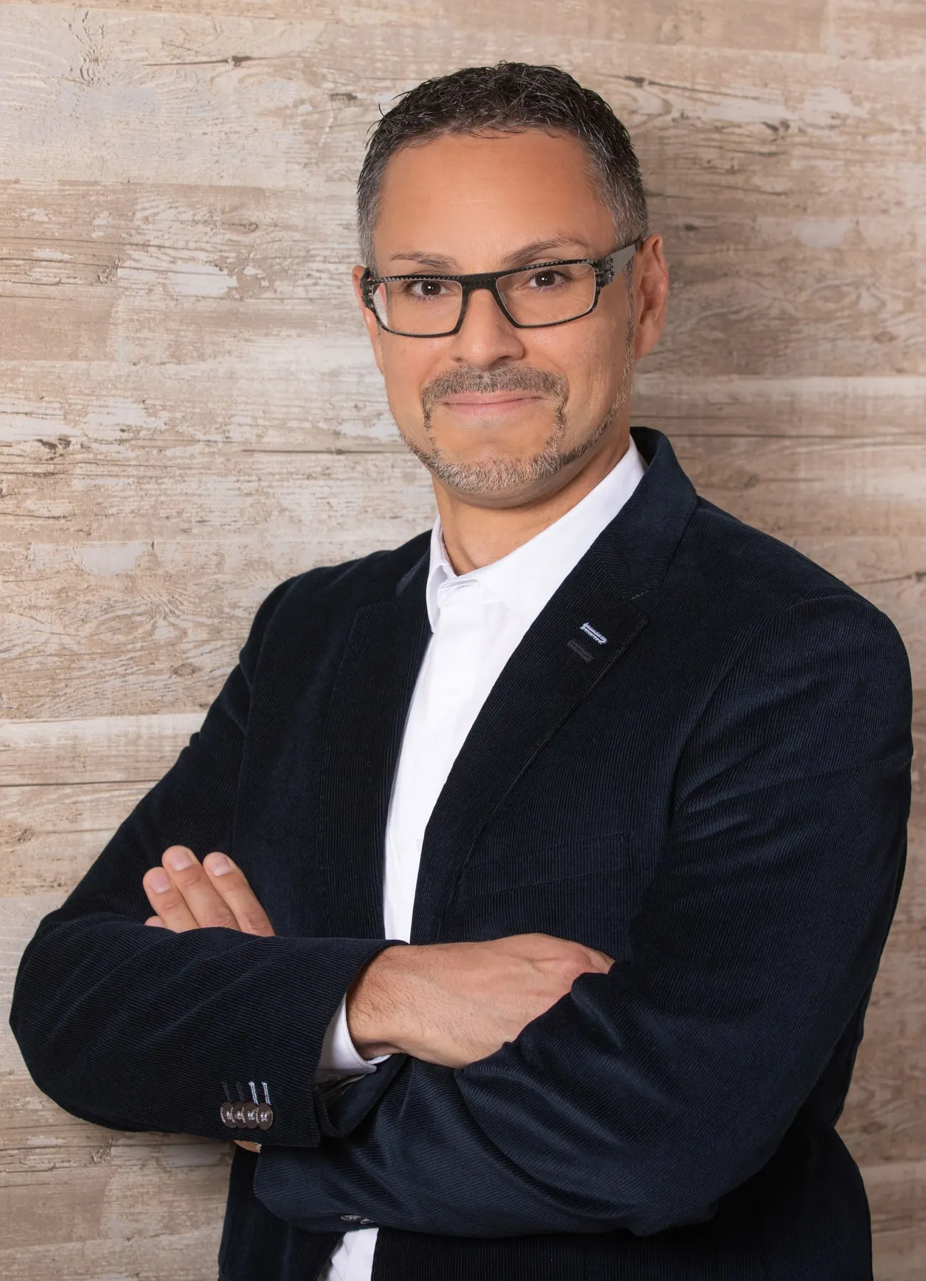 Patrick Schmid im dunklen Sakko, die Arme verschränkt