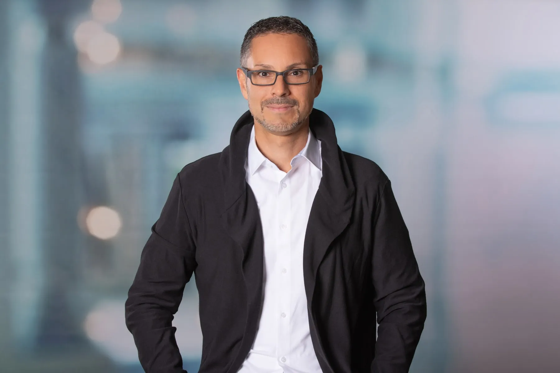Patrick Schmid im Sakko, stehend in einem Bürogebäude