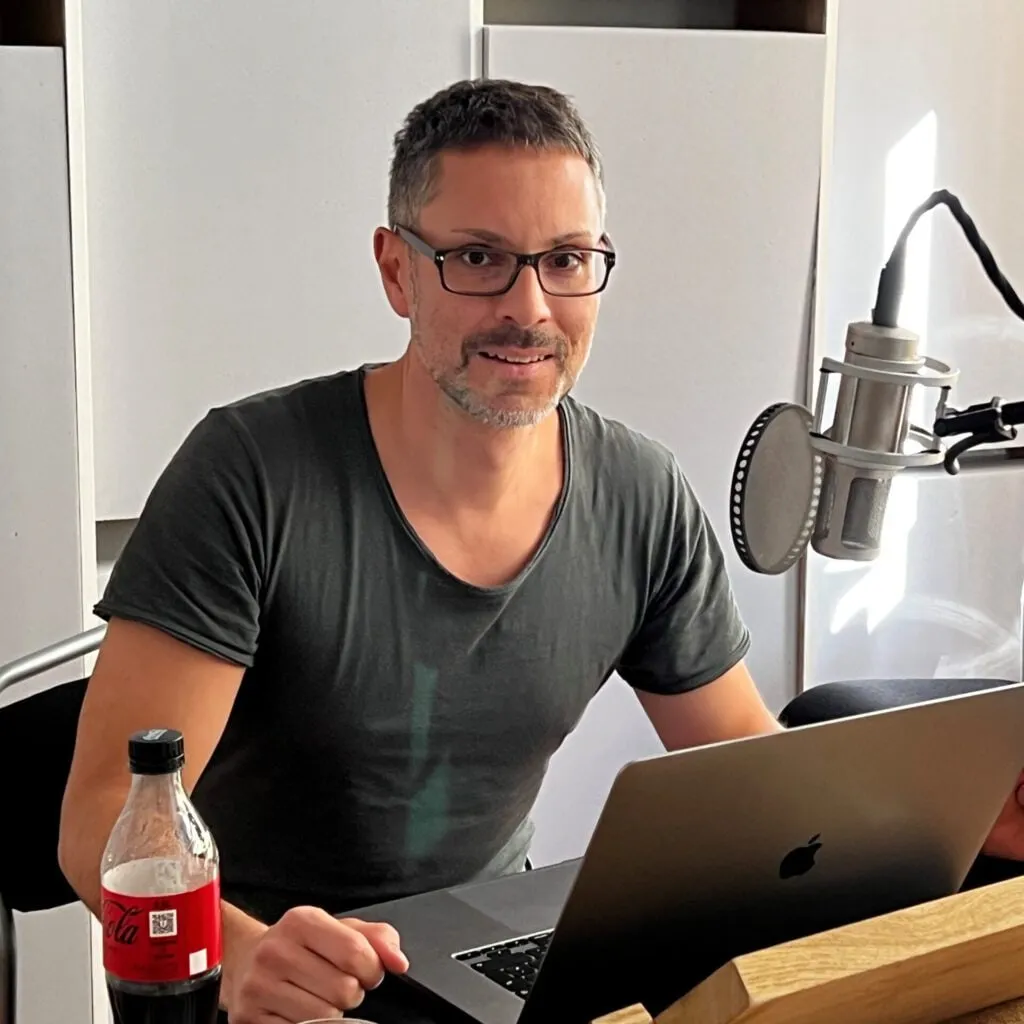 Patrick Schmid am Schreibtisch mit Studiomikrofon und Laptop