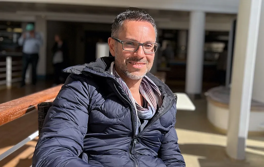 Patrick Schmid in Winterjacke auf einer sonnigen Terrasse